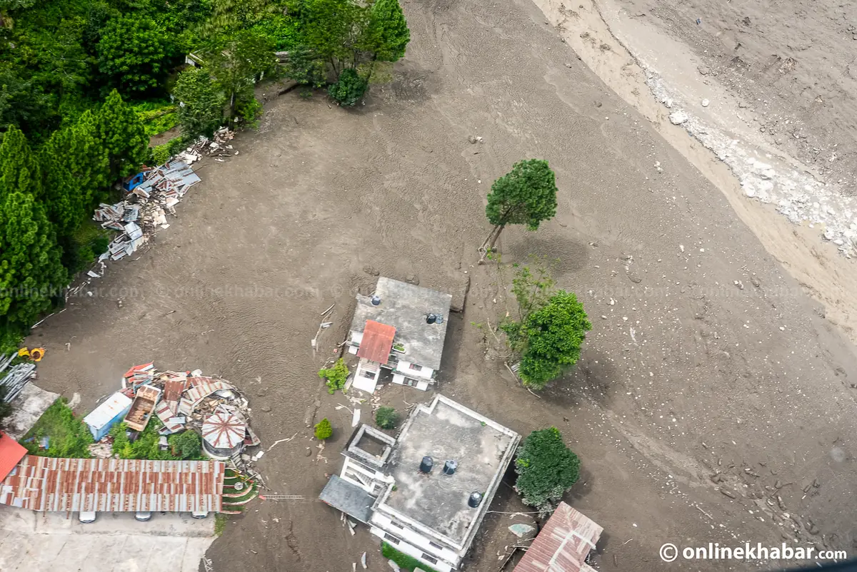 Aerial close view of concrete buildings standing in a flat grey plain of silt with only roofs and upper walls clear