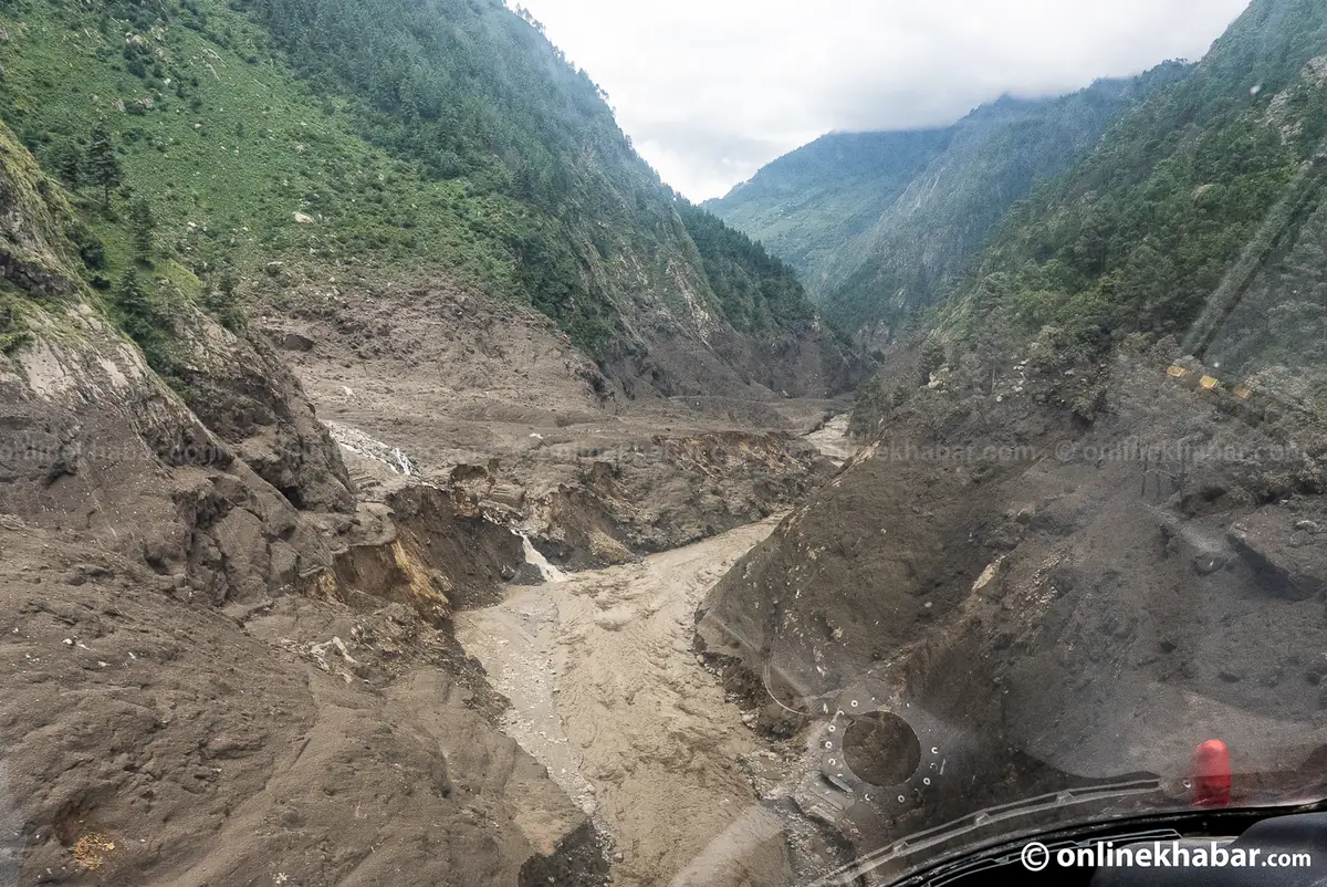 Aerial view of a river gorge stripped back to bare rock and grey debris with a pipeline section visible