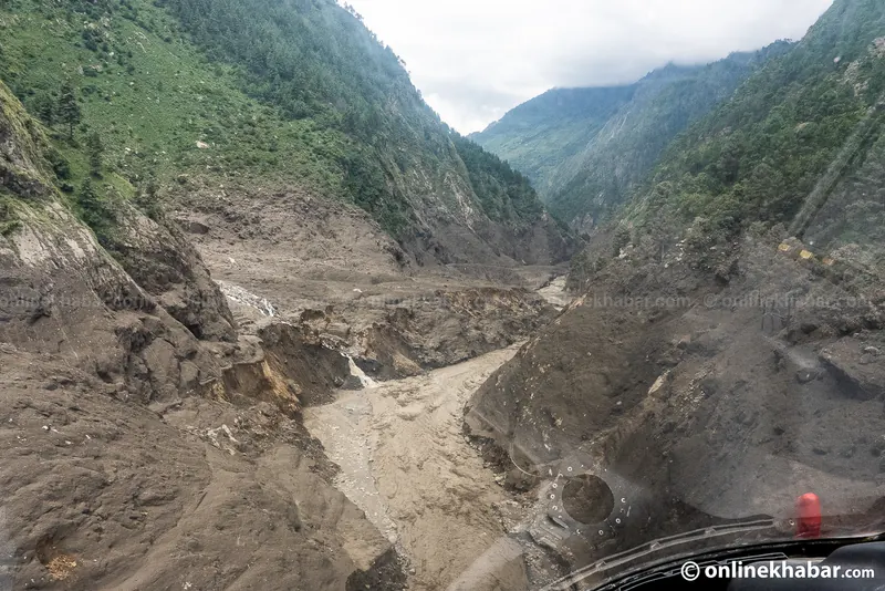 Aerial view of a river gorge stripped back to bare rock and grey debris with a pipeline section visible