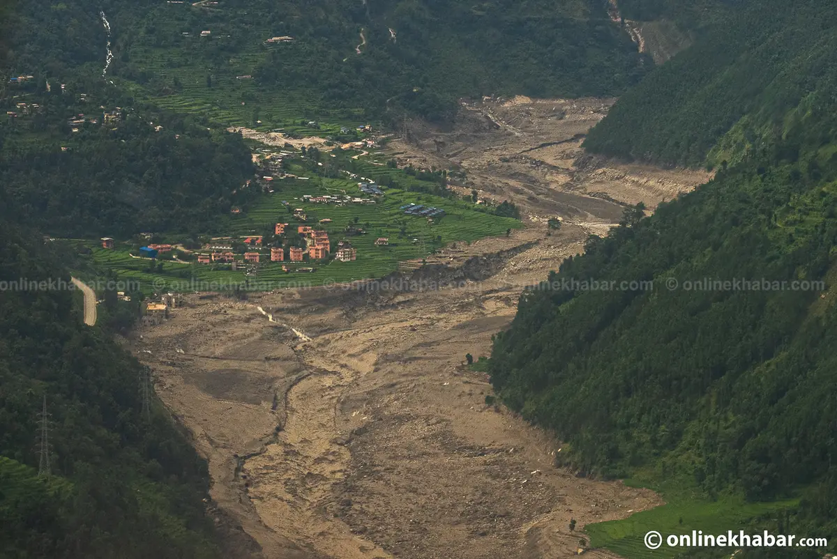 Aerial view of a Rasuwa valley with houses and terraced fields beside a river channel run wide and brown