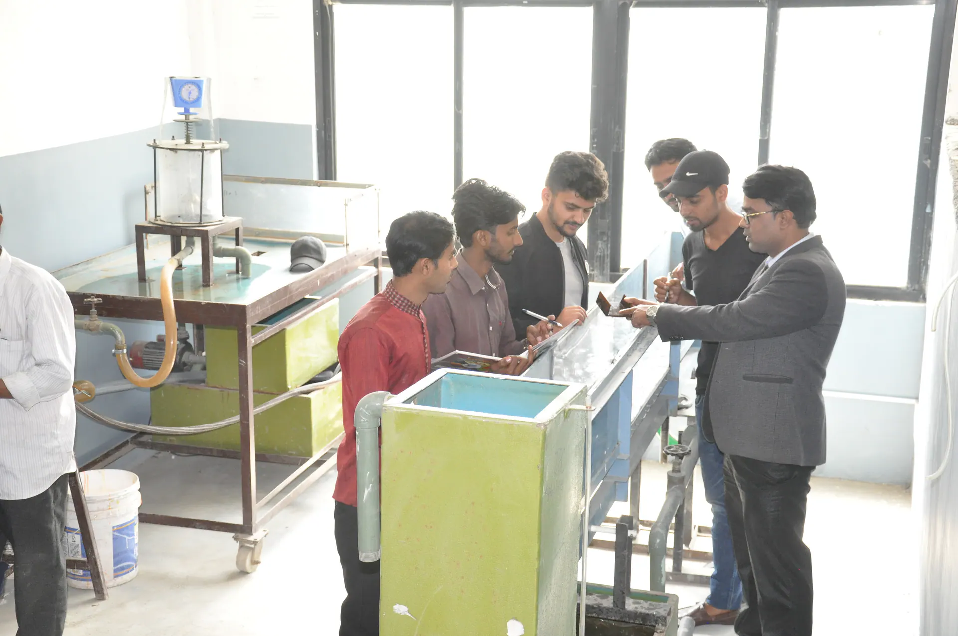 An instructor guiding a group of students during practical engineering work