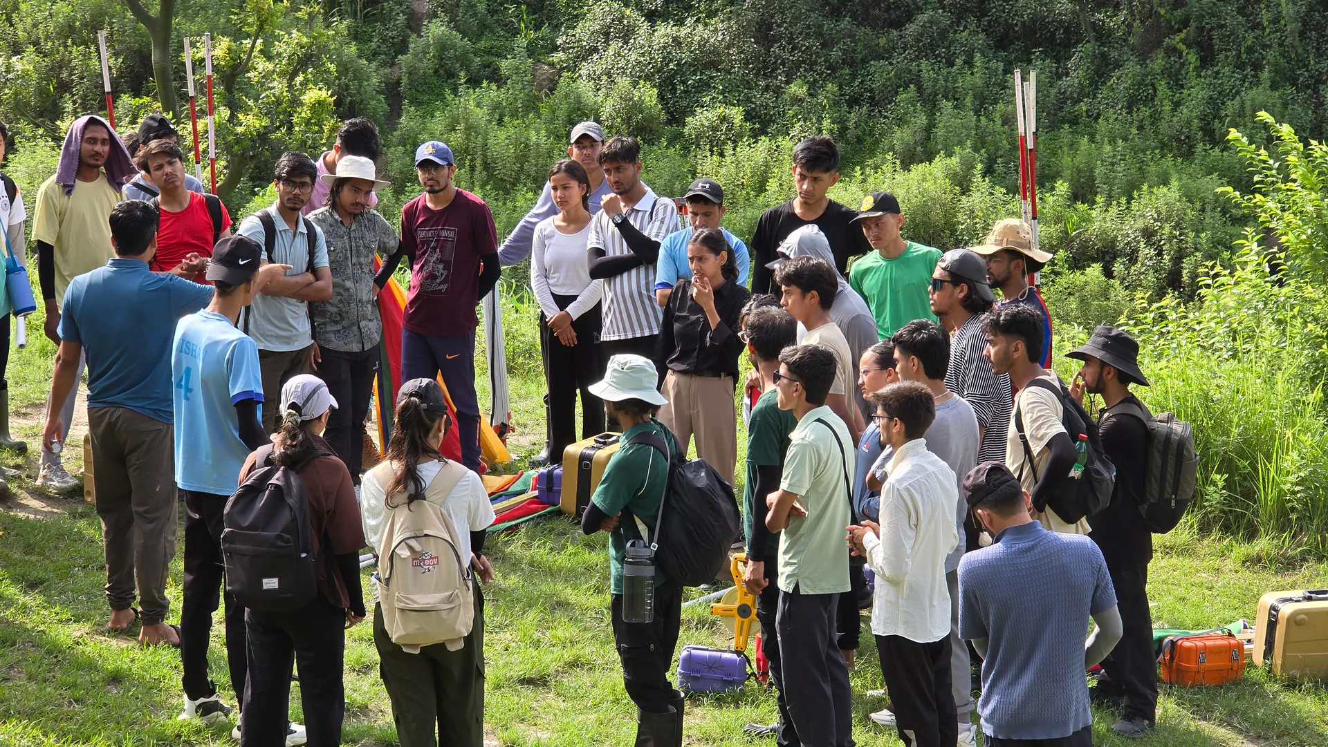 A survey camp group gathered on a hillside around the instruments before starting work